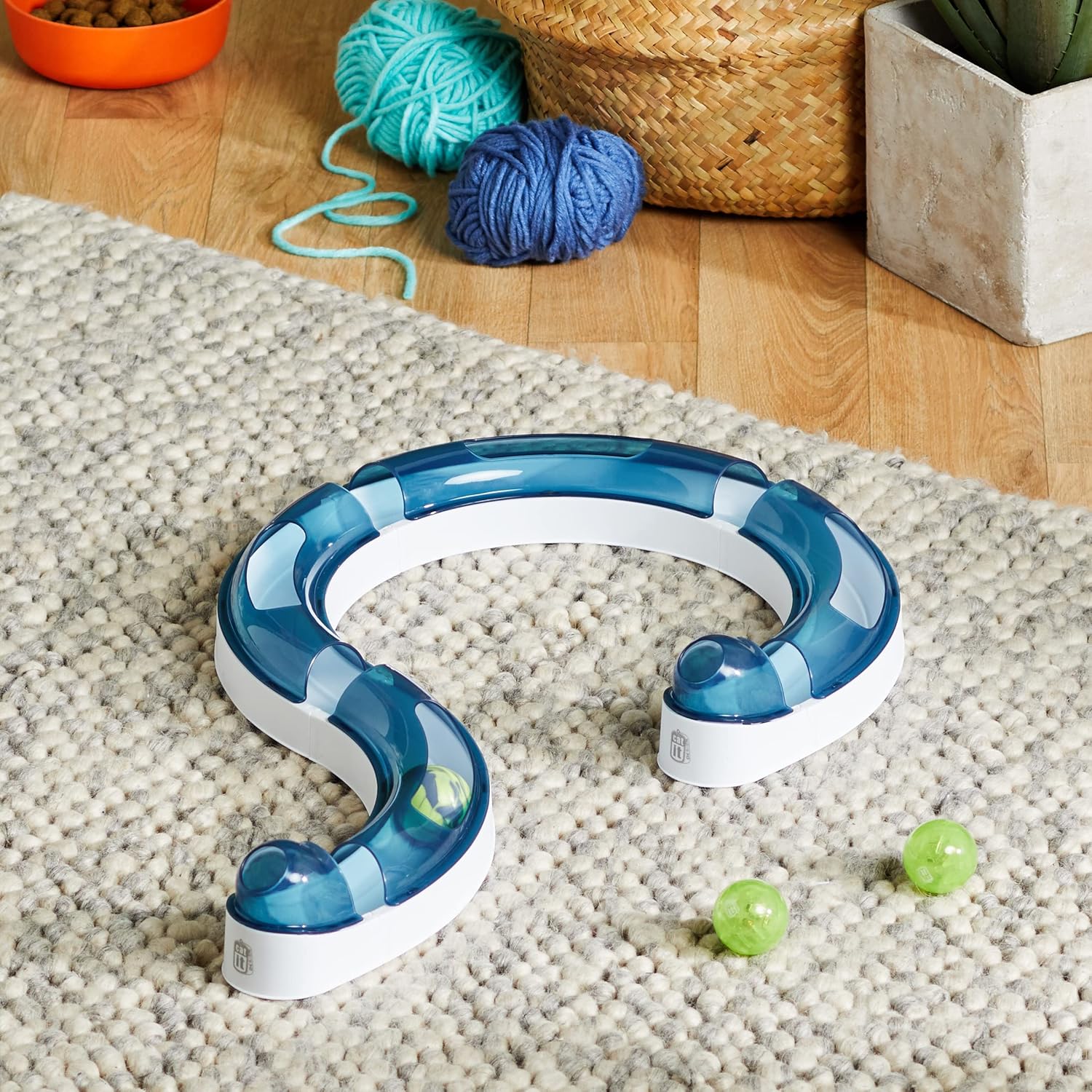Circuit de jeu Catit Senses monté en forme de S, posé sur un tapis texturé avec des balles vertes à proximité.