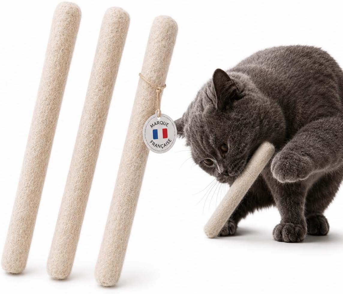 Un chat gris mordant et attrapant fermement un grand jouet en forme de coton-tige fabriqué en laine feutrée.