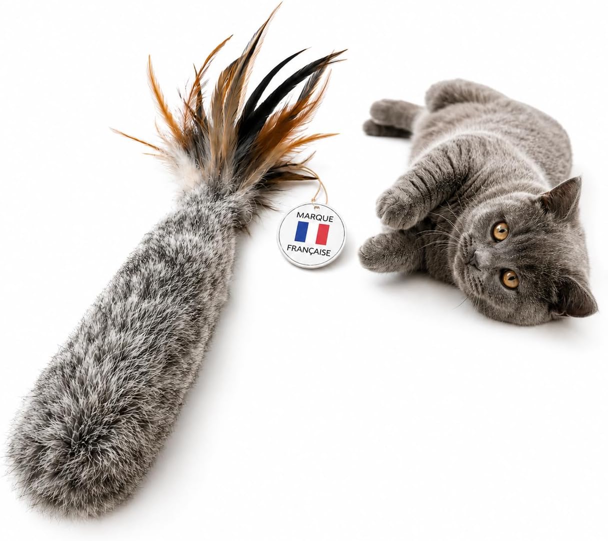 Jouet pour chat en forme de queue en véritable fourrure de lapin grise avec des plumes à son extrémité, posé à côté d'un chat gris.